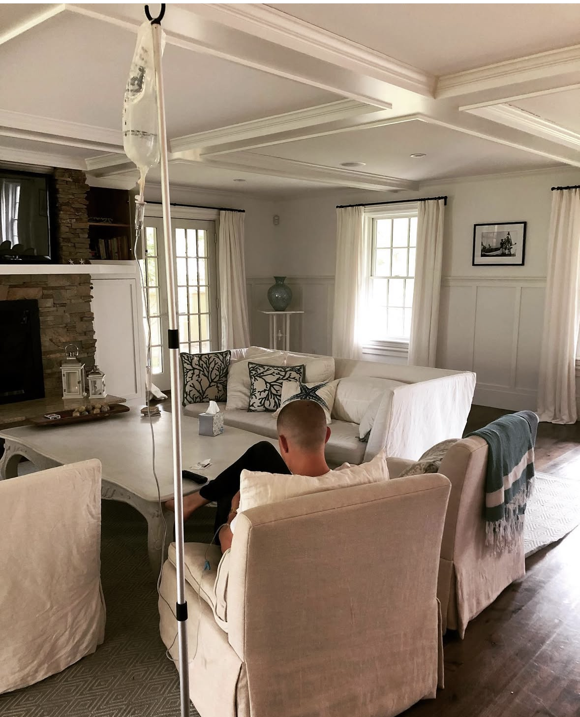 Client resting with an IV drip in a bright living room during a mobile IV house call