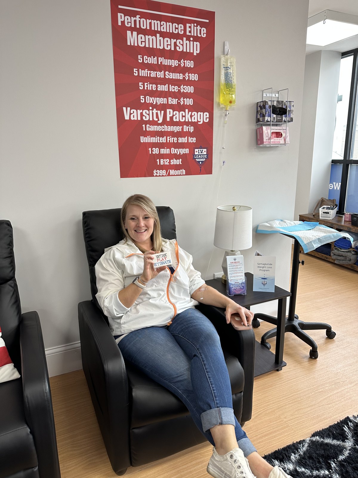 Client holding a Work Play Hydrate card while receiving an IV drip in Boston