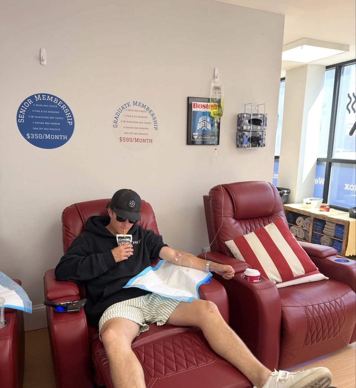 Client relaxing in a red leather recliner while receiving a vitamin IV infusion at IV League Hydration Boston