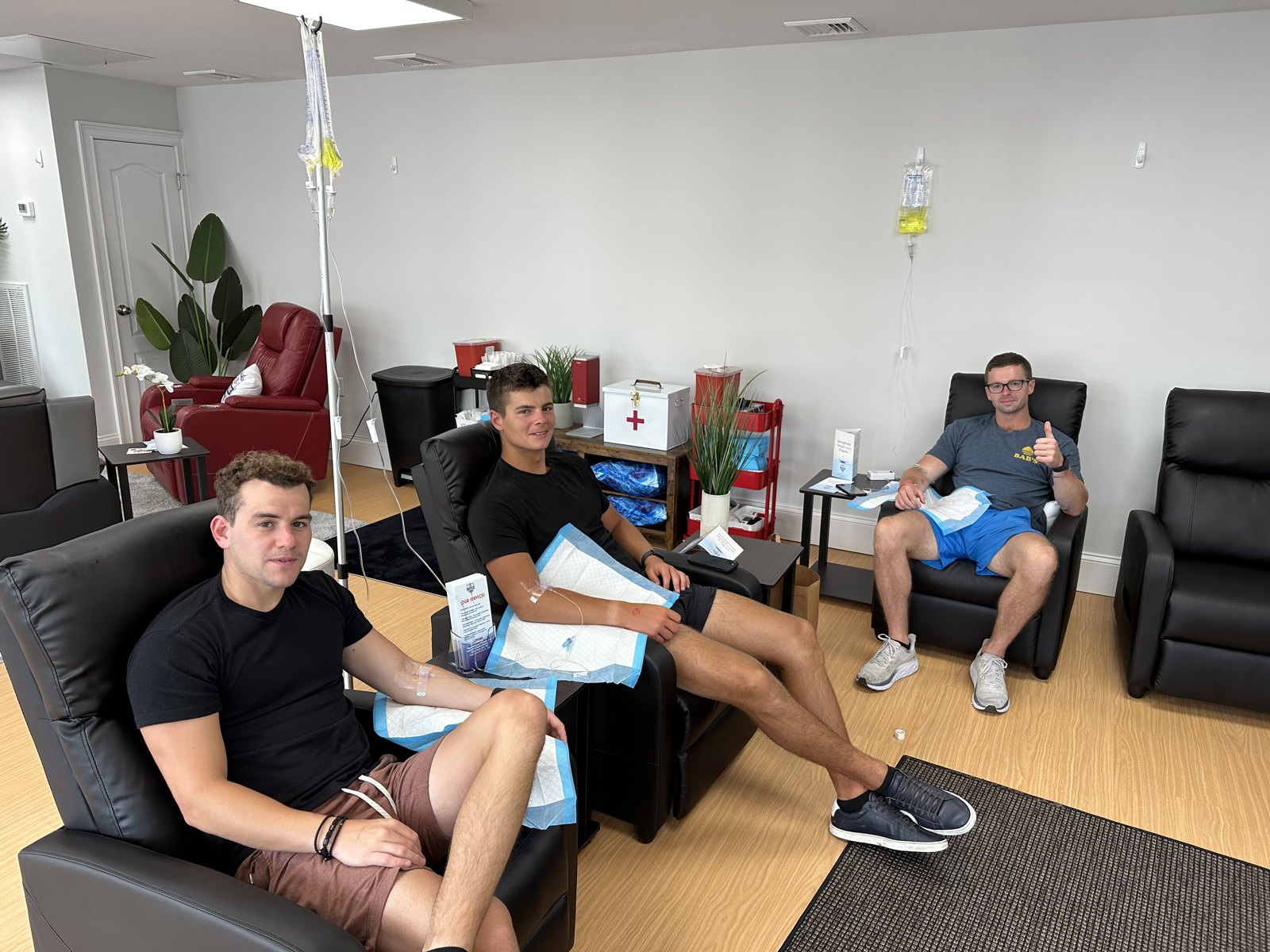 Three friends getting IV drips side by side in the IV League Hydration lounge in Boston