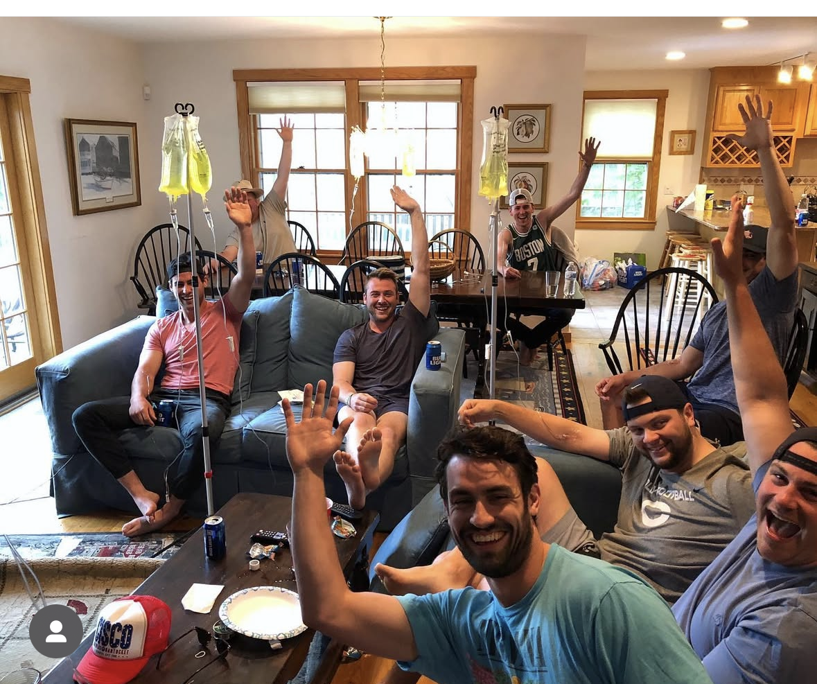 Bachelor party group receiving IV drips together in a rental house living room near Boston