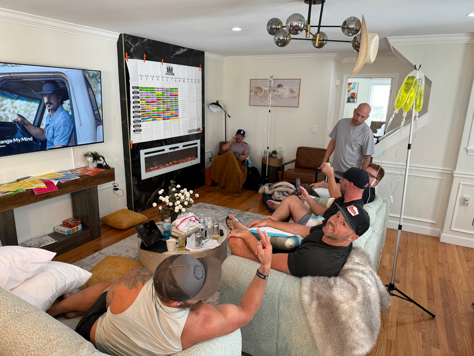 Group of friends watching football at home while receiving mobile IV therapy from IV League Hydration