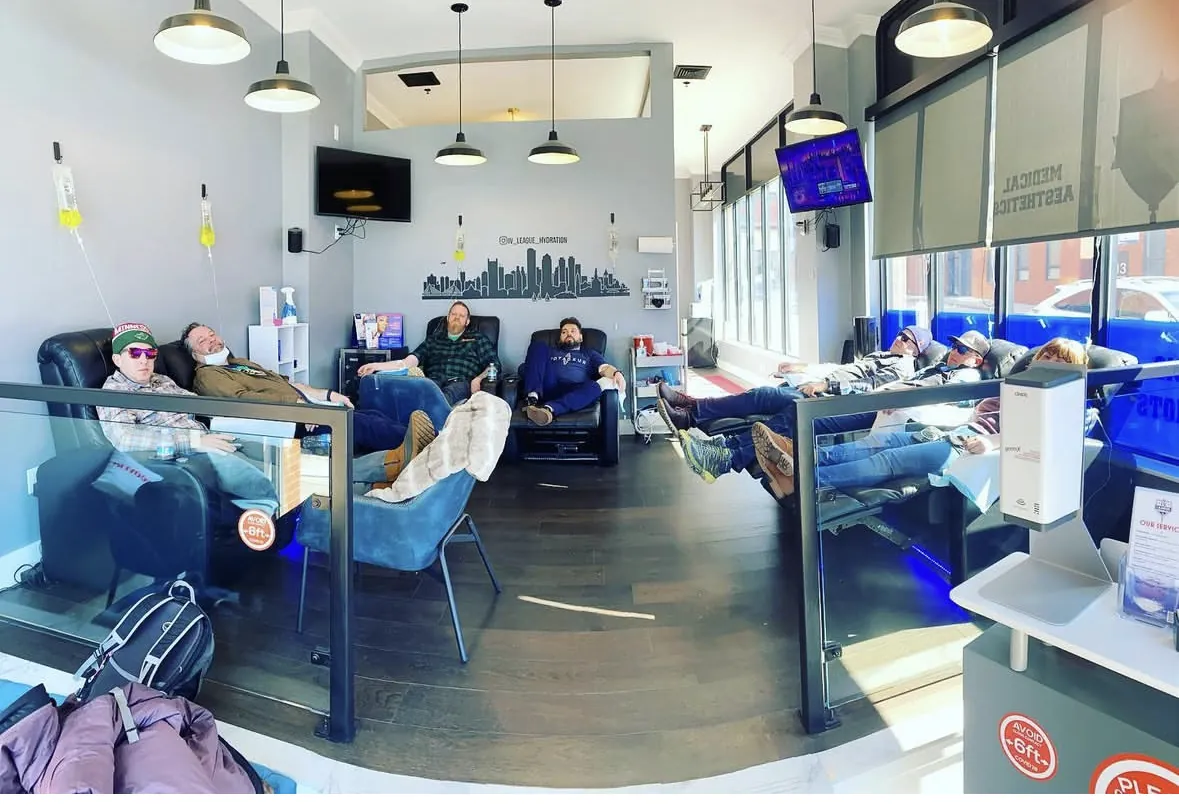 Clients getting IV therapy in recliners under the Boston skyline mural at IV League Hydration in South Boston